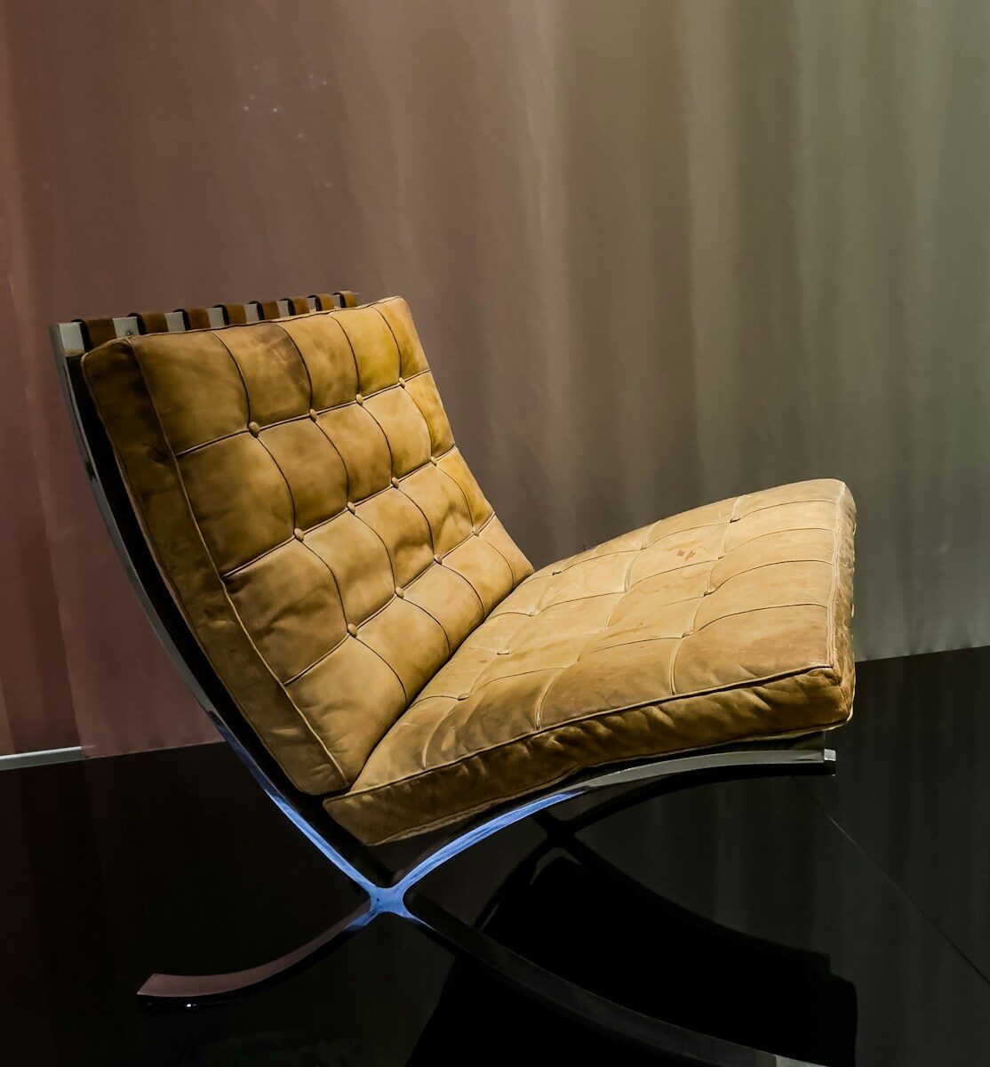 A tufted brown leather lounge chair with chrome legs.