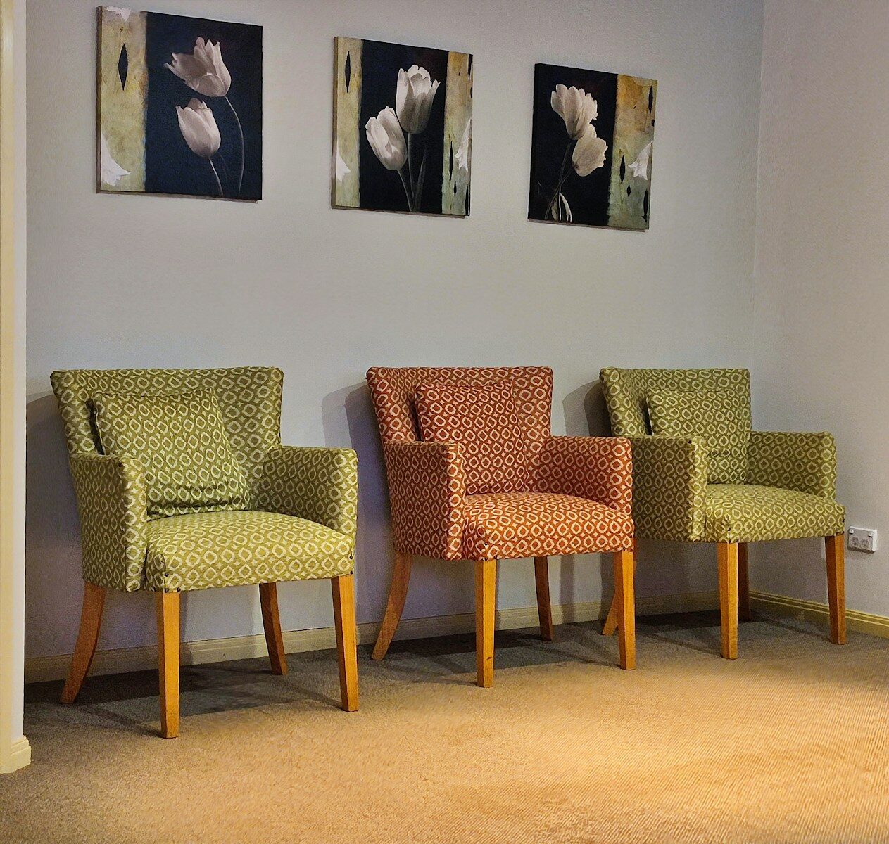 Three chairs in a waiting room with floral art